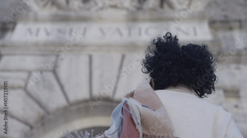 Woman tourist  at Vatican Museum gate with sculpture above entrance. Vatican City, papal enclave of Rome, Italy, slow motion isolated shot