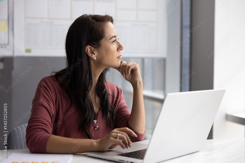 Idea generation and brainstorming. Pensive young woman office worker manager entrepreneur creating strategy plan sitting at desk by notebook ponder business problem solution looking away from screen Idea generation and brainstorming. Pensive young woman office worker manager entrepreneur creating strategy plan sitting at desk by notebook ponder business problem solution looking away from screen