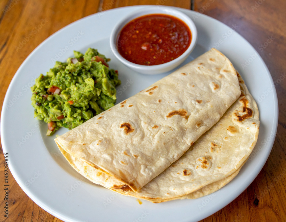 A plate of handmade tortillas served with fresh guacamole and salsa in Costa Rica. A plate of handmade tortillas served with fresh guacamole and salsa in Costa Rica.