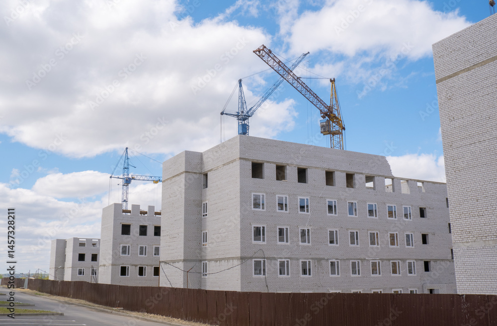 Construction of a new residential complex. Many high-rise cranes and industrial construction equipment against the backdrop of a construction buildings.