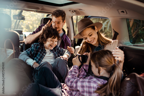 Happy family sitting in car taking pictures during road trip