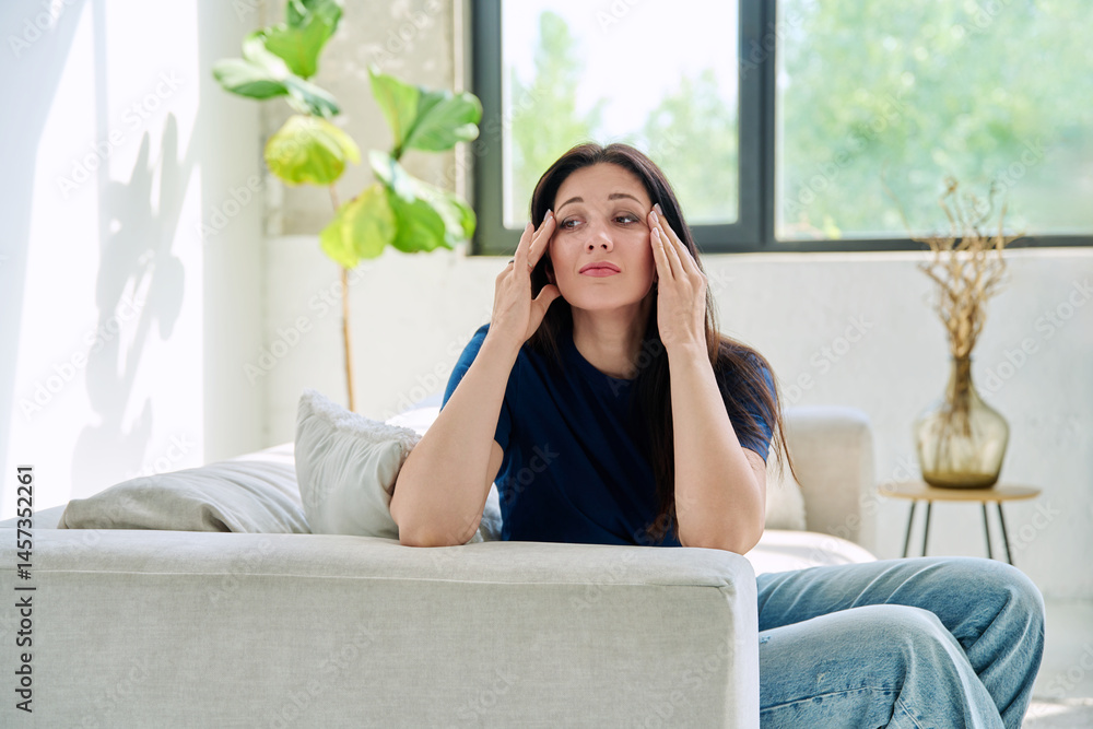 Young woman experiencing stress headache sitting on sofa at home