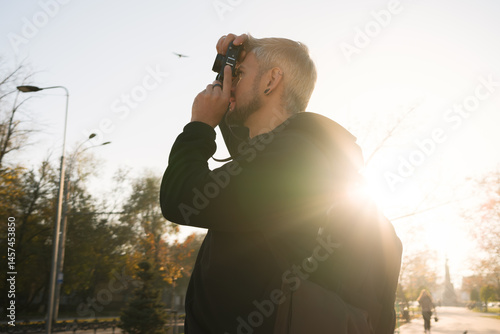 Obraz na plátně Backlit outdoor photo of a person using a camera in warm sunlight