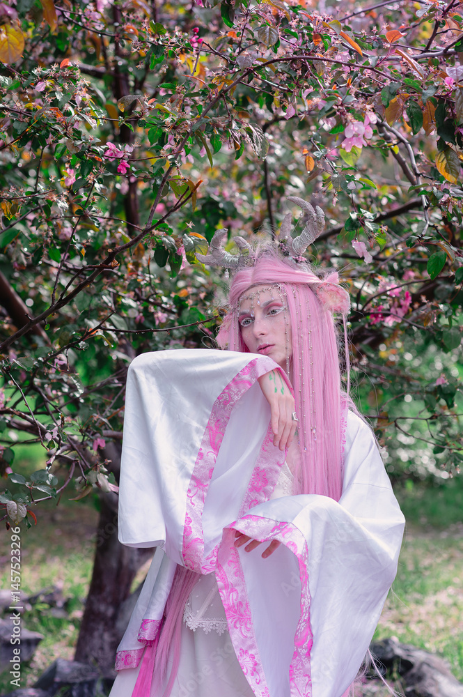 Deer dryad girl against the background of a blooming pink apple tree