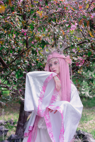 Obraz na płótnie Deer dryad girl against the background of a blooming pink apple tree w salonie
