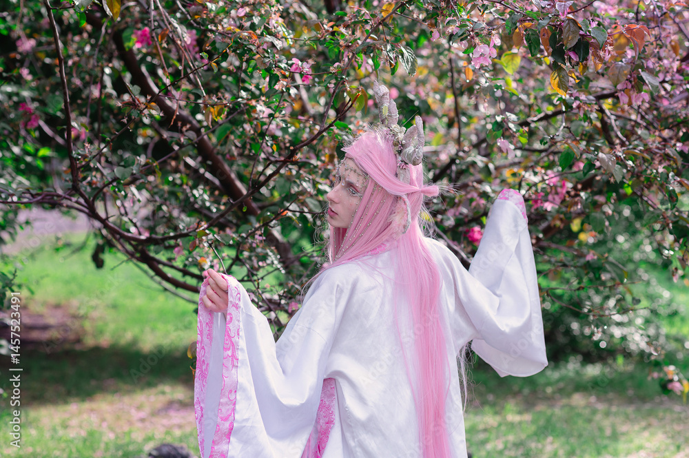 Deer dryad girl against the background of a blooming pink apple tree