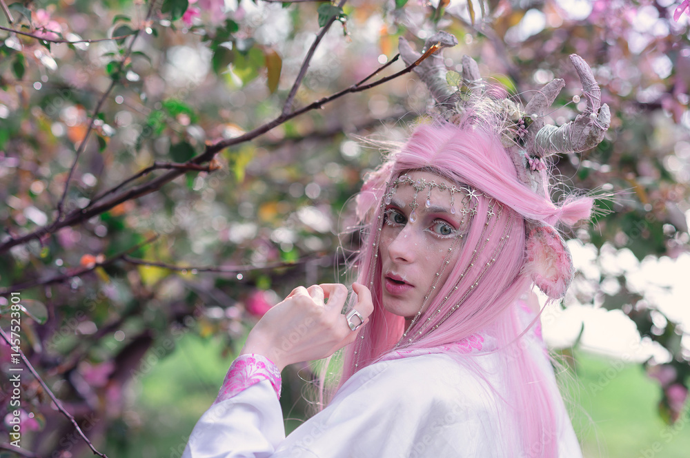 Deer dryad girl against the background of a blooming pink apple tree