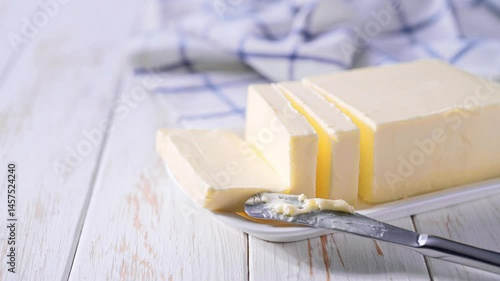 piece of butter in a white ceramic butter dish on a light table.
    Block of fresh butter in a white dish on a kitchen table .