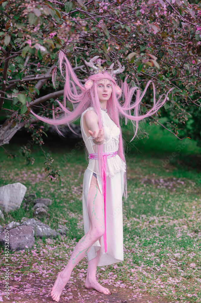 Deer dryad girl against the background of a blooming pink apple tree