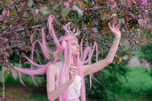 Deer dryad girl against the background of a blooming pink apple tree