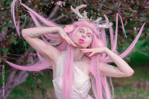 Deer dryad girl against the background of a blooming pink apple tree