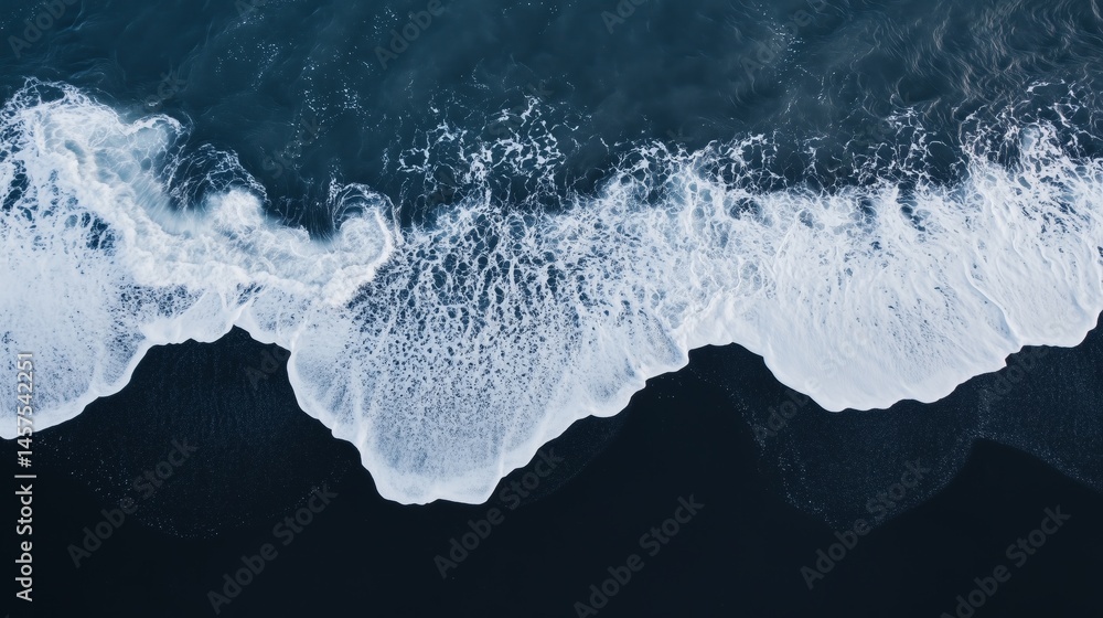 Aerial perspective of waves crashing onto a black basaltic sand beach