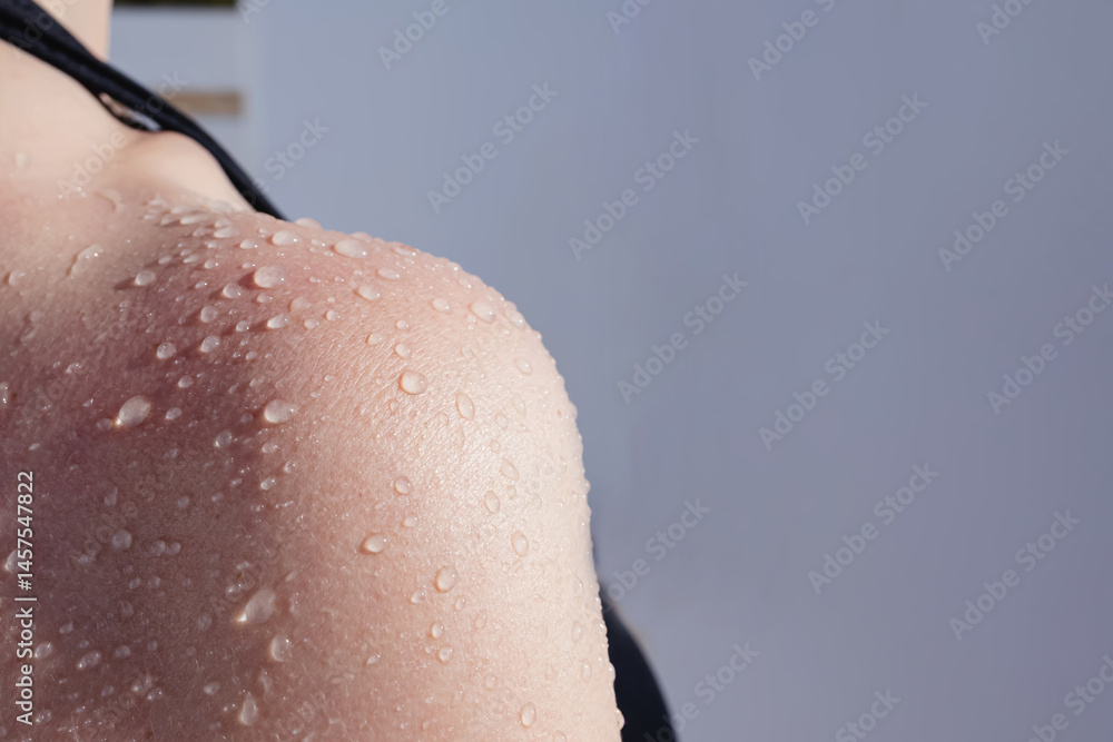 Fototapeta premium Close-up shot of water droplets on a sun-kissed shoulder