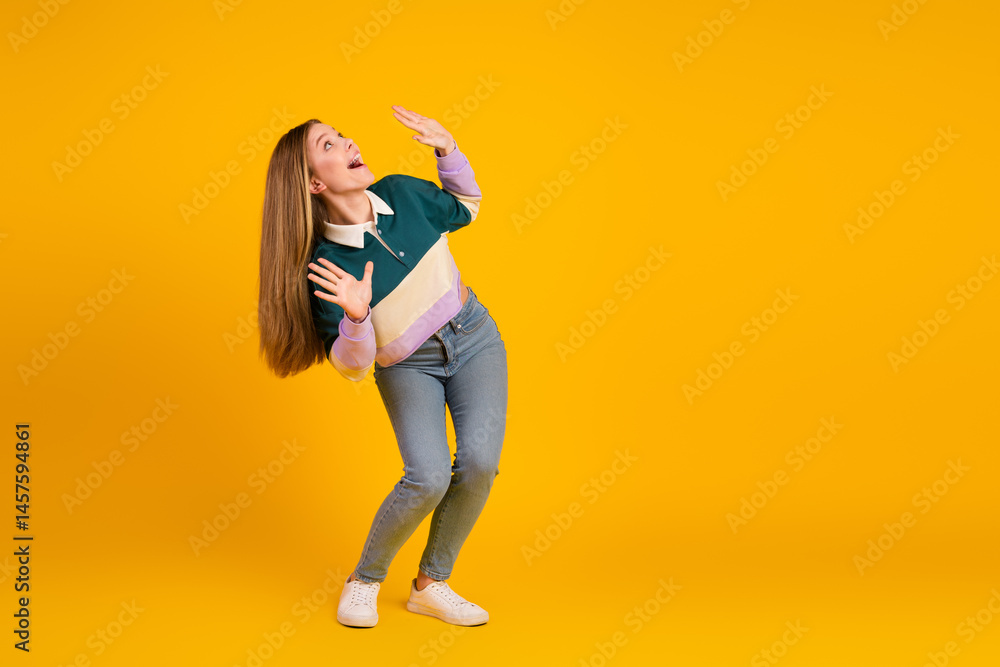 Young woman in casual style gesturing on vibrant yellow background showcasing trendy fashion attire and youthful charm