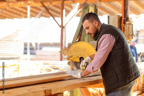 Young carpenter sawing wood...