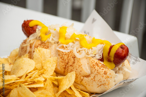 Fotografie bock wurst hot dog sausage with sauerkraut and mustard served with potato chips