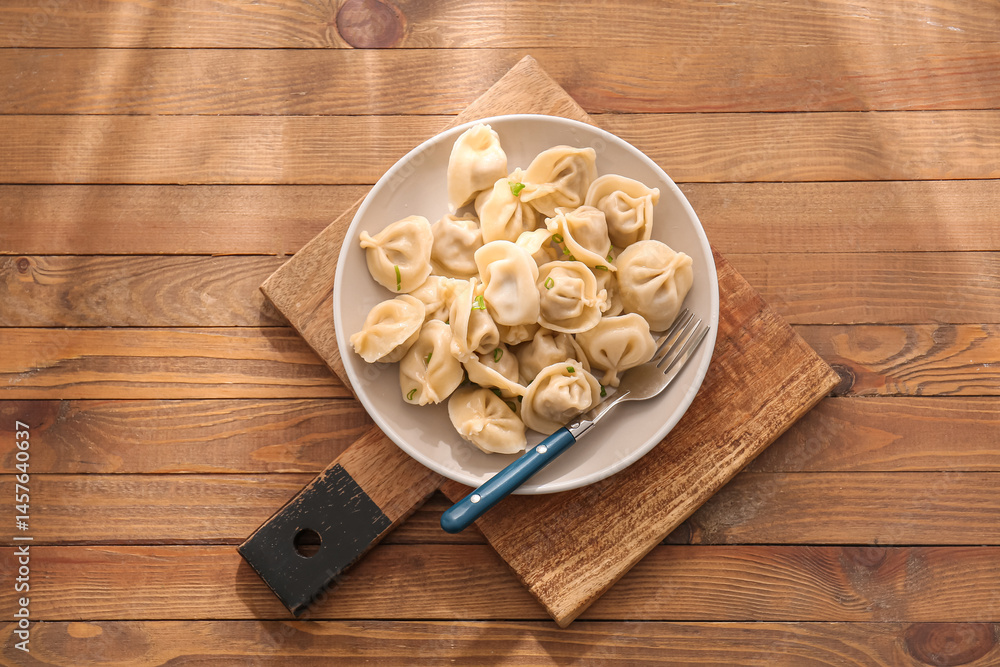 Plate with delicious boiled dumplings on wooden background Plate with delicious boiled dumplings on wooden background