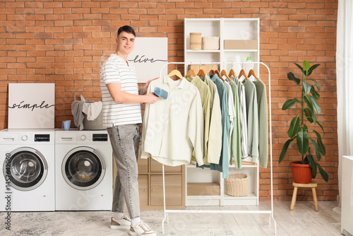 Young man steaming clothes ...