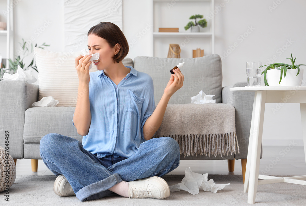 Allergic young woman with tissue and nasal drops sneezing at home Allergic young woman with tissue and nasal drops sneezing at home