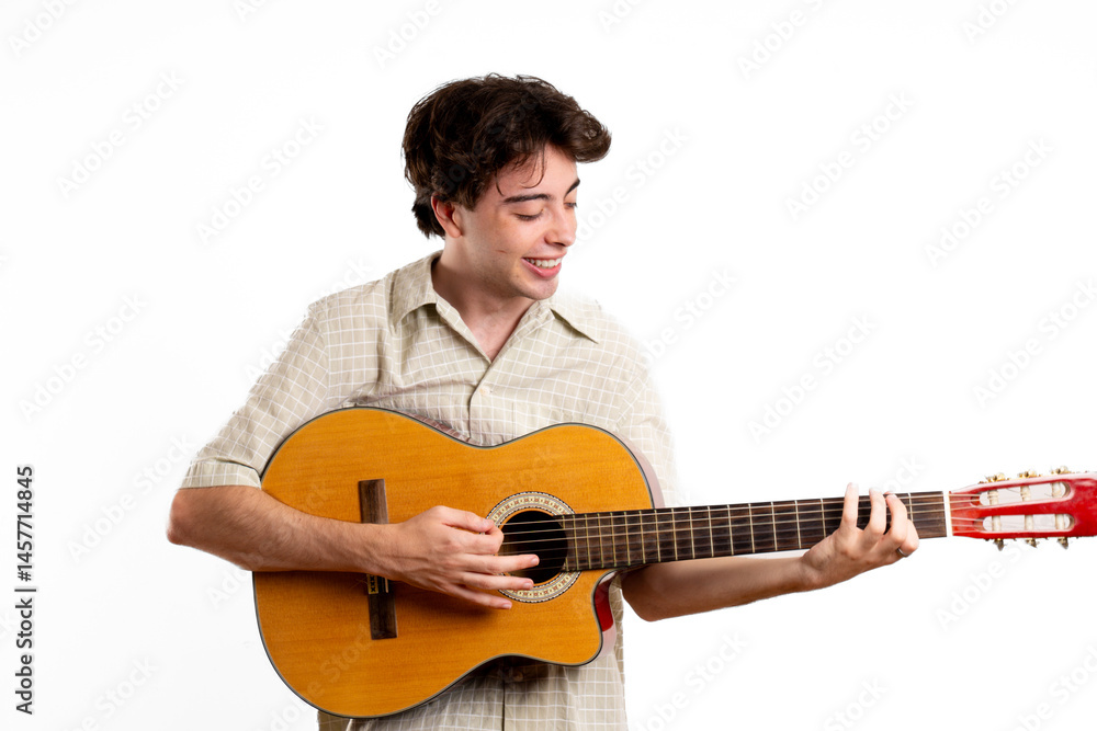 Obraz premium Young Latin man happily looks at his guitar and plays it, in white setting