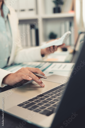 Young female accountant hand holding business investment analysis pen. Accounting, finance expert working with financial data and calculations with graph paper document. Vertical close up.