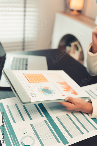 Obraz na płótnie Young female accountant hand holding business investment analysis pen. Accounting, finance expert working with financial data and calculations with graph paper document. Vertical close up. w salonie