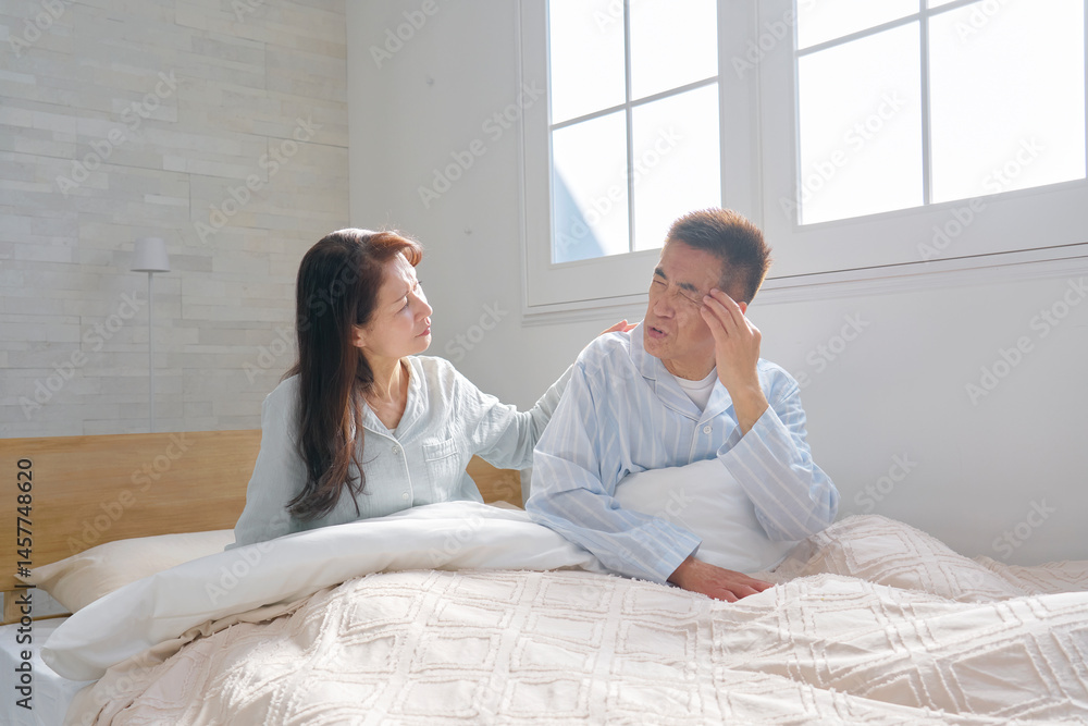 Fototapeta premium ベットの上で頭痛がする中年の男性