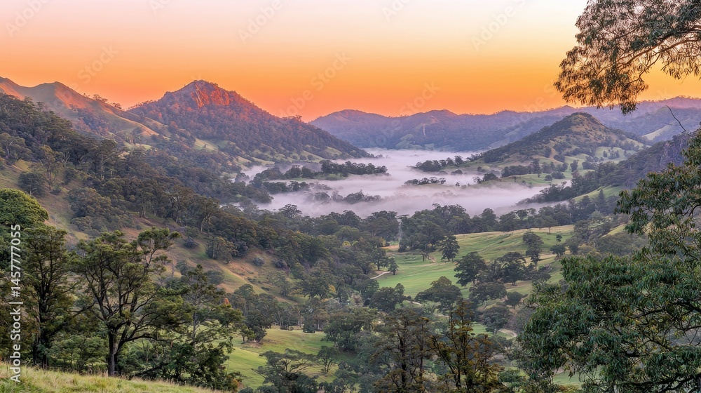 Fototapeta premium Serene Sunrise Over Misty Valley with Rolling Hills and Majestic Mountains in Background