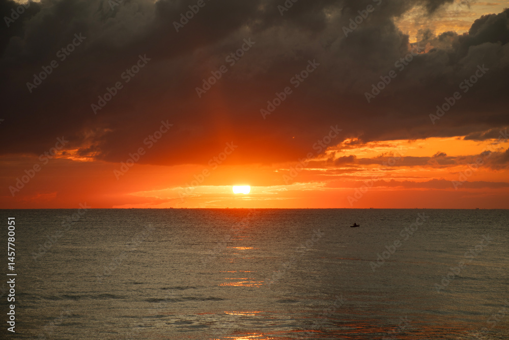Sunrise on land facing the sea on a calm beach with clouds and fishing boat fetching the net Sunrise on land facing the sea on a calm beach with clouds and fishing boat fetching the net
