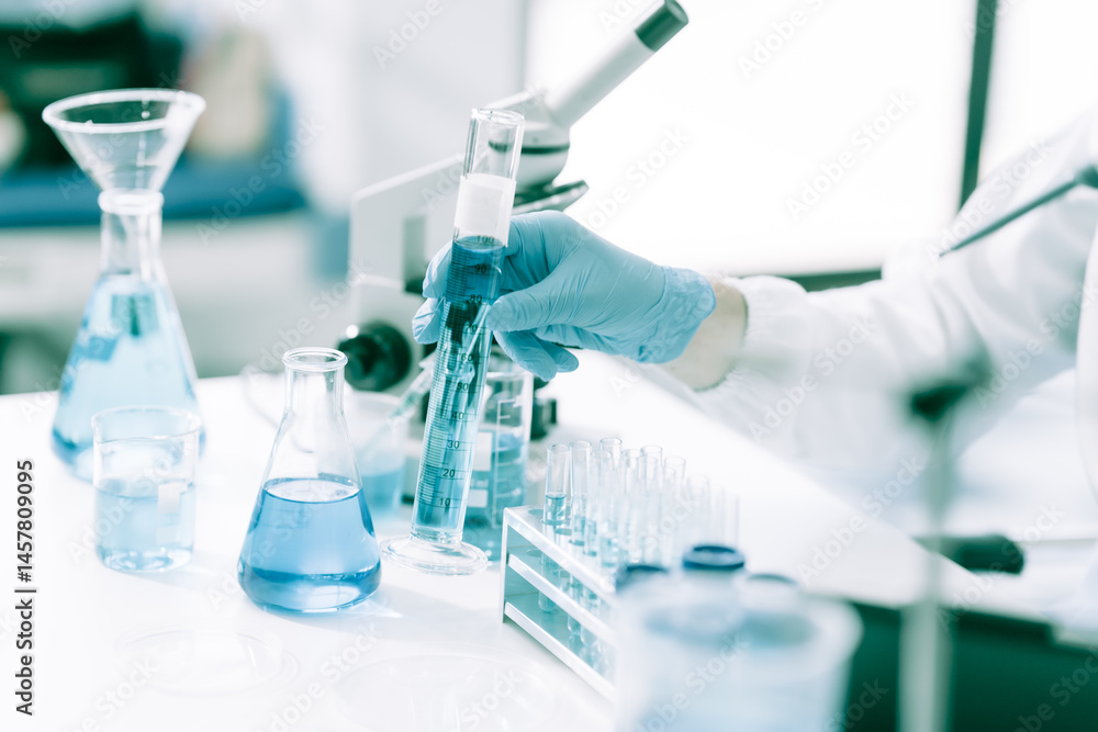 A white male scientist at a table, studying blue substances in test tubes and bottles, using a microscope for chemical research in pharmaceuticals, analyzing compounds for medical advancements