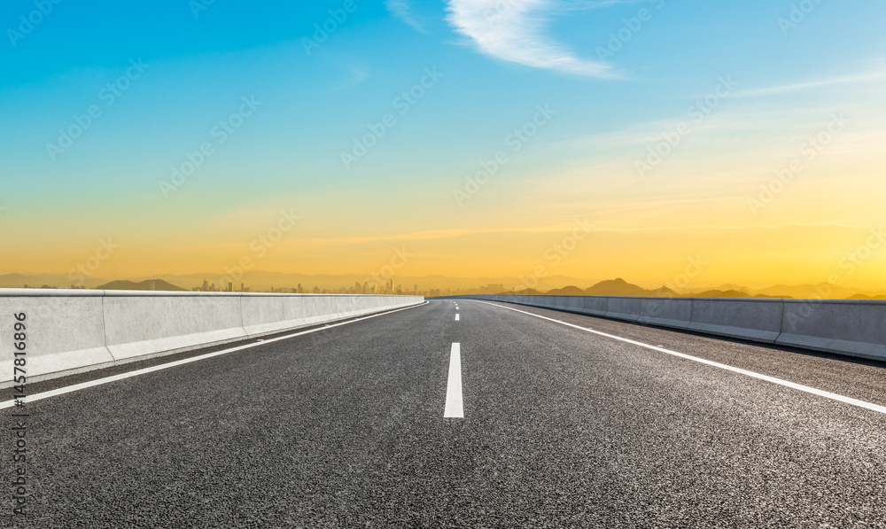 Naklejka premium Asphalt highway road and city skyline with beautiful sky clouds at sunset