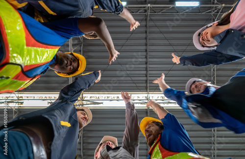Foto Worker in safety gear stand in a circle, shouting and raising their hand in the air