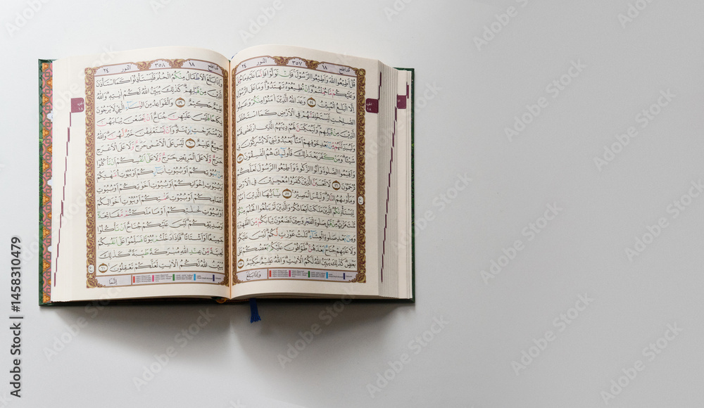 Obraz premium Bandung, Indonesia - 02.11.2025: Photo of opened Holy Quran with Arabic calligraphy on white background