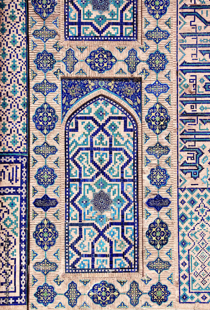Fototapeta Vertical background with detail of ancient mosaic walls with clay details and geometric ceramic tile ornament. Traditional iranian tile decorations. Text on wall is a quote from Quran