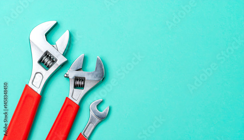 Wallpaper Mural Adjustable wrenches in three sizes with red handles are arranged on vibrant turquoise background, showcasing their versatility and functionality for various tasks Torontodigital.ca