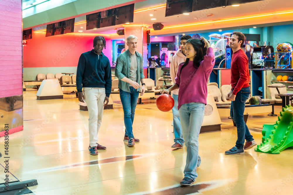 Young woman throwing bowling ball with multiethnic friends cheering