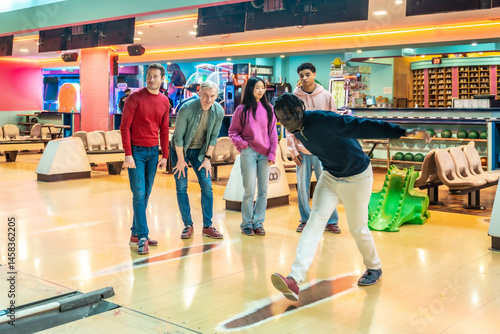 Obraz na płótnie Young man bowling with friends cheering him on w salonie
