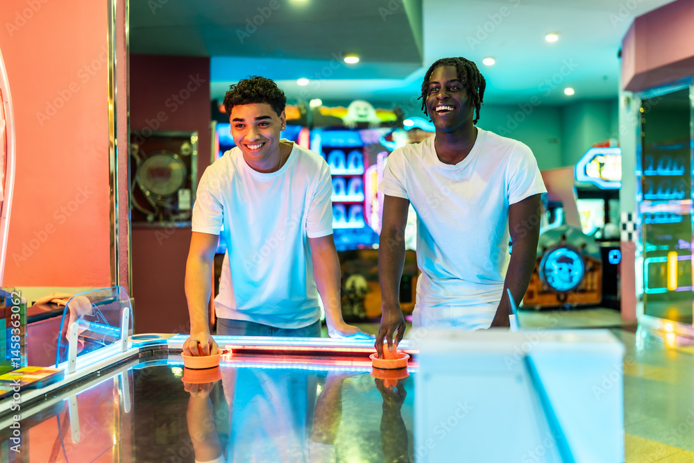 Two friends playing air hockey, enjoying weekend in amusement arcade