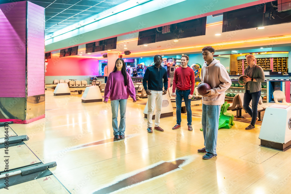 Young multiethnic friends enjoying bowling together at a colorful alley