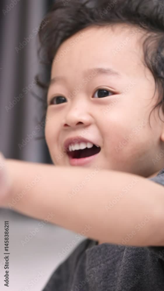 Asian toddler looking at the camera with gentle eyes and raised hand, capturing innocence and emotional connection. Asian toddler looking at the camera with gentle eyes and raised hand, capturing innocence and emotional connection.