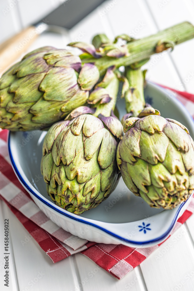 Fototapeta premium Ripe artichokes plant in bowl on white table.