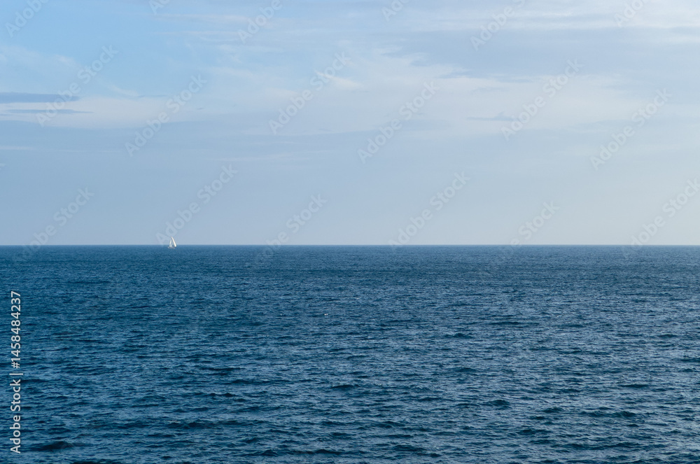 Obraz premium Blue sea and sky and single sailboat 