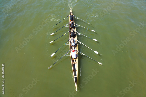 Foto Academic rowing, four athletes with a coxswain sail in a boat on open water