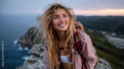 Smiling young woman hiking on cliff edge overlooking ocean during sunset, adventurous outdoors photography