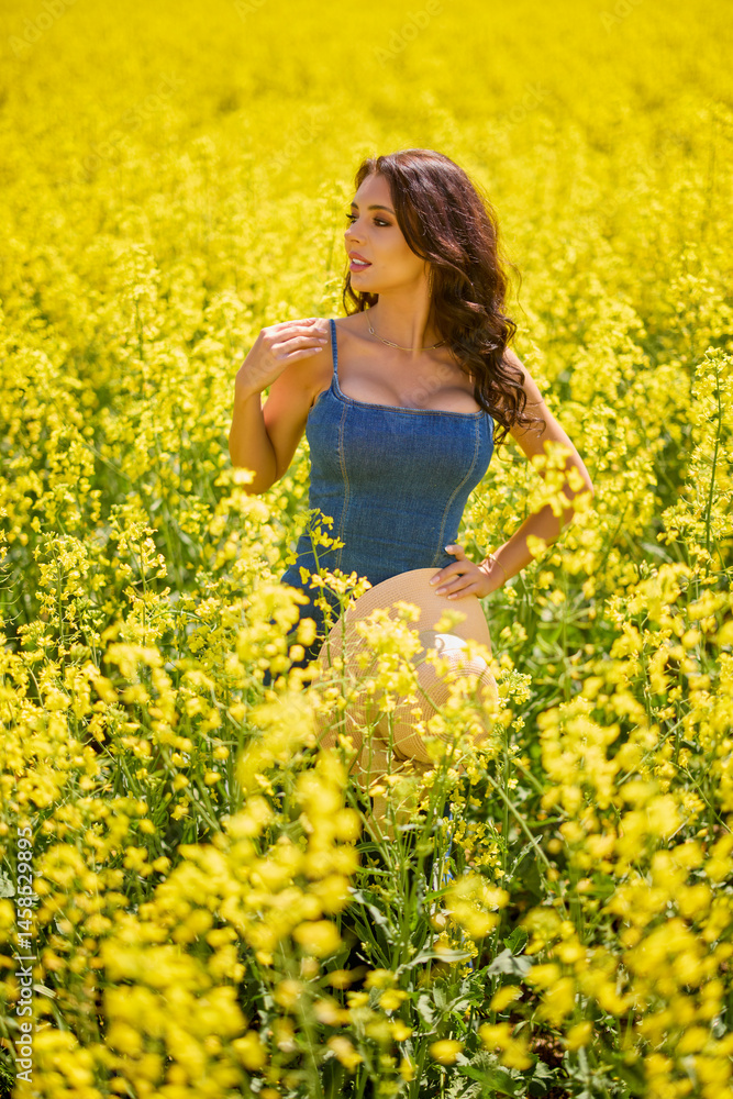 beautiful woman with a hat posing in the blooming rapeseed field on a sunny day beautiful woman with a hat posing in the blooming rapeseed field on a sunny day