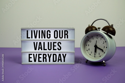 Slika na platnu Living our values everyday text on LED lightbox with alarm clock on purple backg