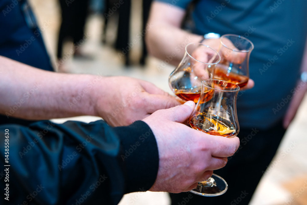 Close-up of two hands holding glasses of cognac or brandy