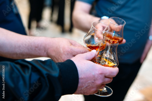 Close-up of two hands holding glasses of cognac or brandy
