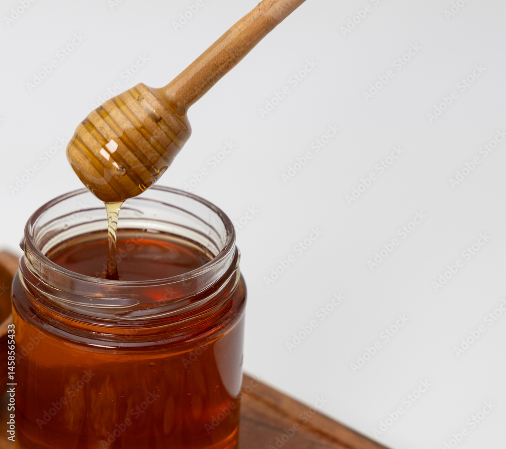 Close up shot of honey dripping from honey dipper in a jar of honey Close up shot of honey dripping from honey dipper in a jar of honey
