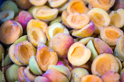 Close-up of shock-frozen ripe pink-back apricot halves with a thin ice coating. Are prepared for retail packaging to ensure extended shelf life in supermarkets and maintain perishable harvest quality.
